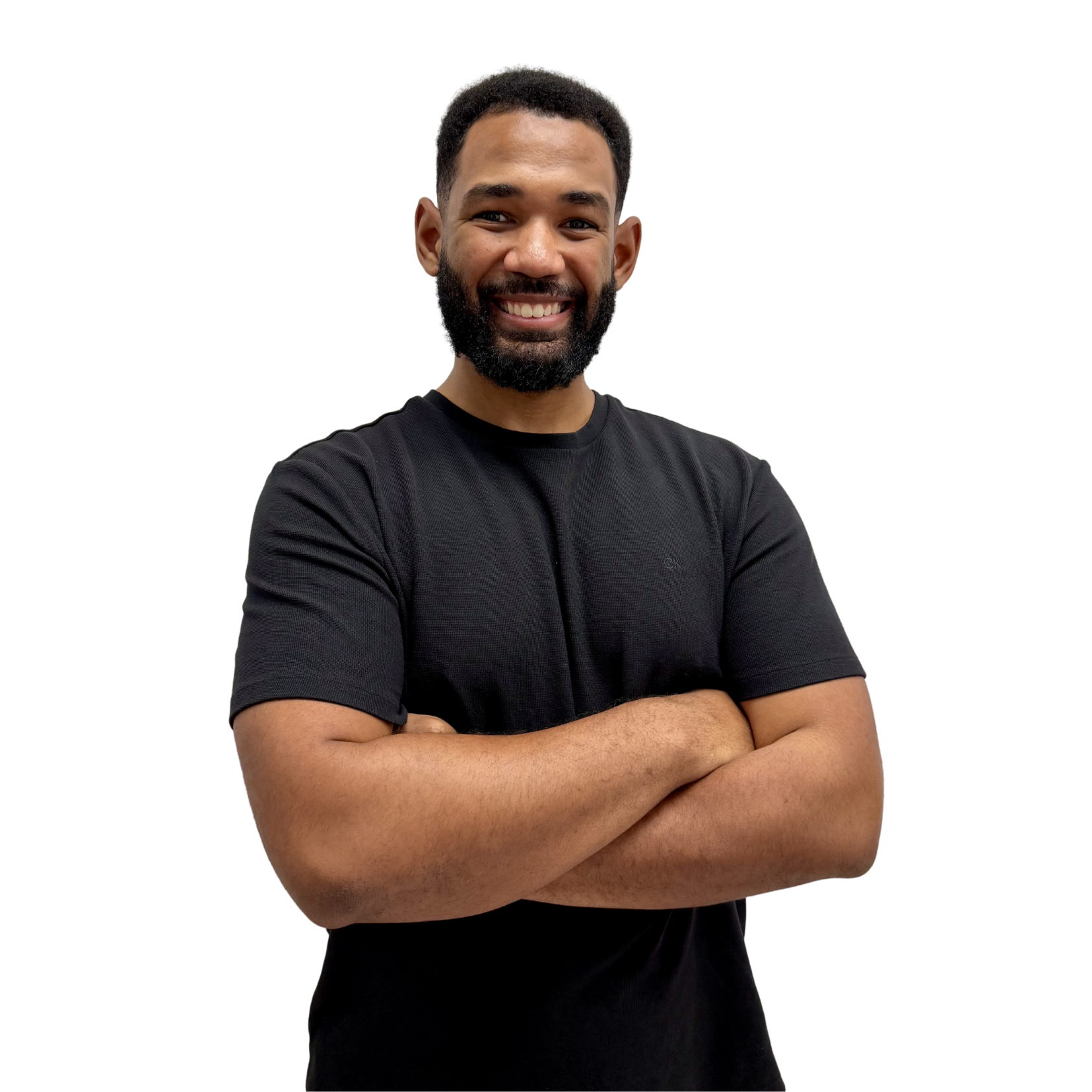 Smiling man with a beard and short hair, wearing a black T-shirt, arms crossed against a white background.