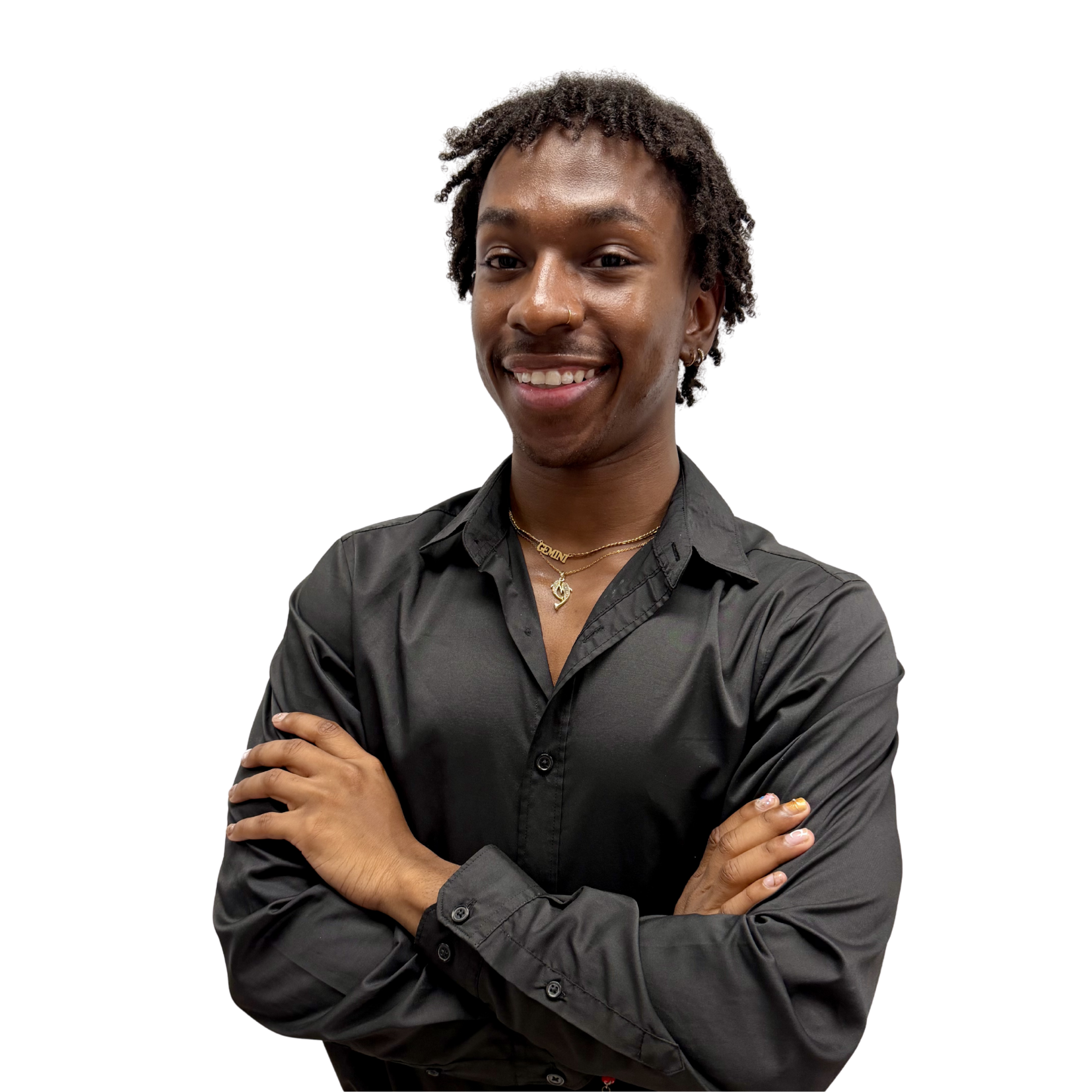 Smiling young man with braids, gold necklaces, and crossed arms wearing a black shirt against a white background